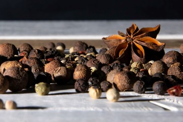 Loose dry spices, whole peppers brown, white and red, anise  on white wooden background