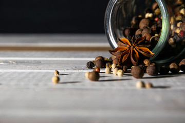 Loose dry spices, whole peppers brown, white and red, anise in inverted glass transparent can on...