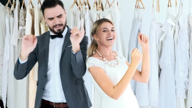 Romantic wedding couple in expensive dress shop. White man and woman in bride dress, man dancing together with his woman. Romantic young couple concept.