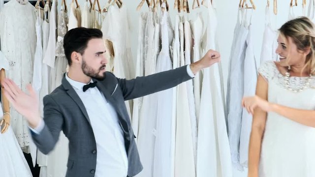 Romantic wedding couple in expensive dress shop. White man and woman in bride dress, man dancing hard toward his woman, scaring her. Romantic young couple concept.