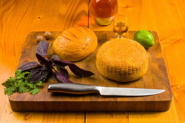 national Adyghe cheese homemade on a cutting Board with a knife, Basil, parsley, lime, sesame oil,...