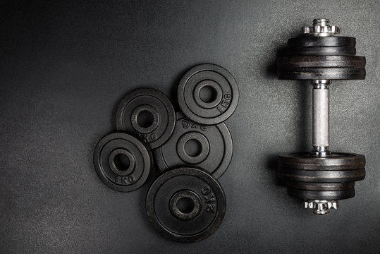 Gym dumbbells with black metal weights 1kg and 2kg on black background with copy sapce, Photograph taken from above