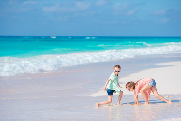 Little girls having fun at tropical beach playing together at shallow water