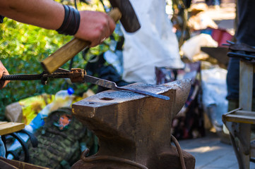 blacksmith performs the forging of hot glowing metal on the anvil