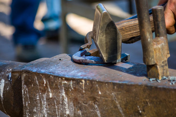 blacksmith performs the forging of hot glowing horseshoe on the anvil