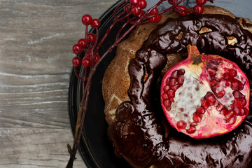 Homemade chocolate cake with pomegranate on  wooden background
