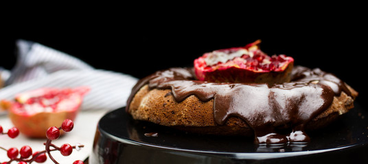 Homemade chocolate cake with pomegranate on  wooden background