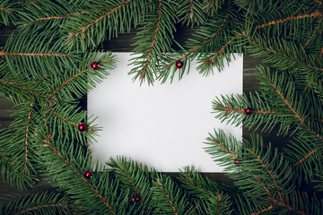 Creative layout made of Christmas tree branches with paper card note. Flat lay. Nature New Year concept.