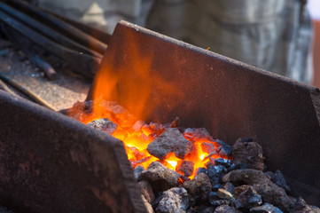blacksmith furnace with burning coals, tools, and glowing hot metal workpieces