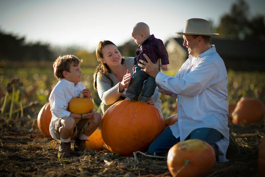 Happy family having fun together in a pumpkin patch.