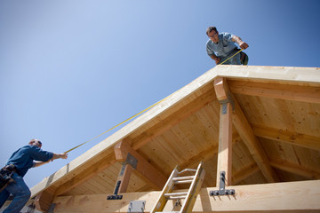 Two male builders building a house.