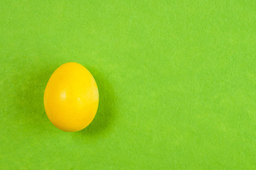 yellow painted easter chicken egg on green background