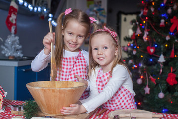 Two little girls make gingerbread cookies for Christmas