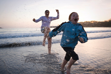 Young girl being splashed by her older sister at the beach.