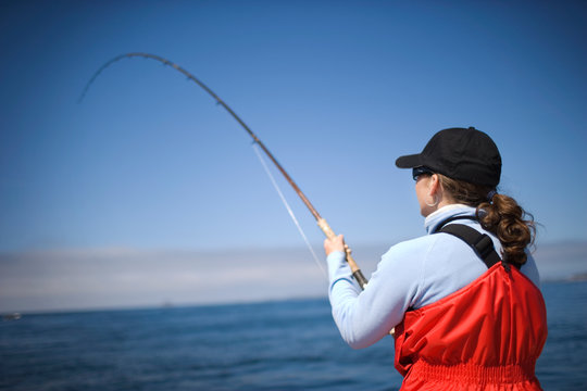 Woman fishing with a rod in the ocean.