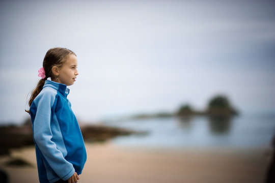 Young girl standing on a beach.