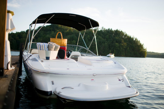 Boat with towels and a picnic basket on a lake.