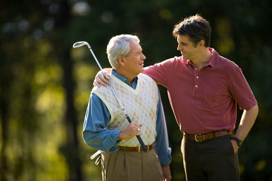 Man with his arm around father on golf course