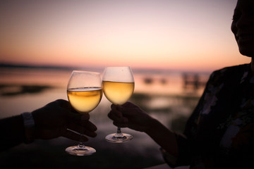 Glasses of wine being toasted at sunset.