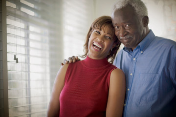 Portrait of a mature adult man with his arm around his mid-adult daughter.