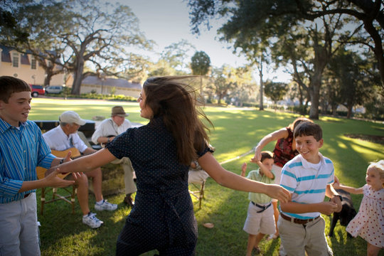 Teenage girl dancing with young teenage boys while family dance to mature men playing guitars.