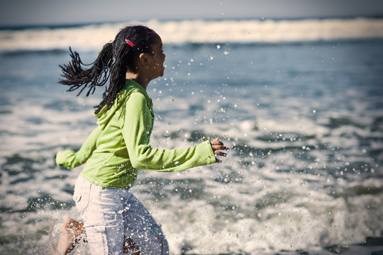 Girl running through water at a beach.