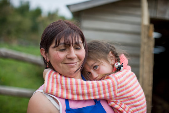 Young girl with her arms around her mother's neck.