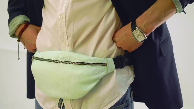 Young man with white fanny pack on hips poses during photo session