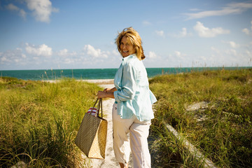 Mature adult woman running towards the ocean at a beach.