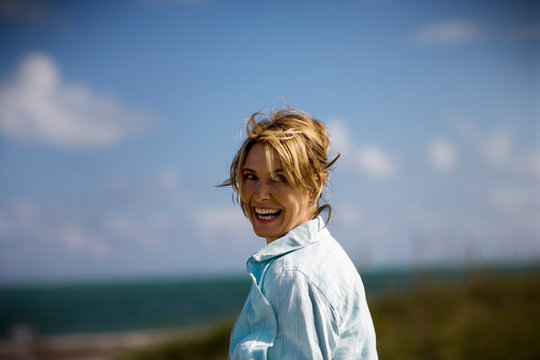 Mature adult woman walking towards the beach.