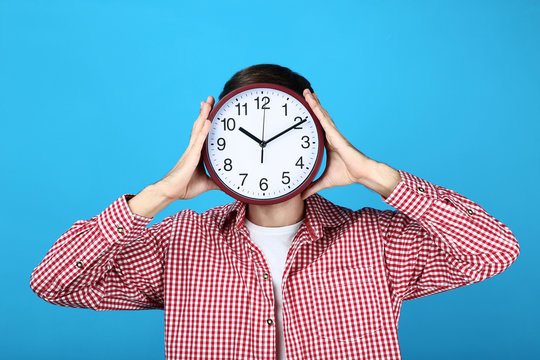 Beautiful young man with round clock on blue background