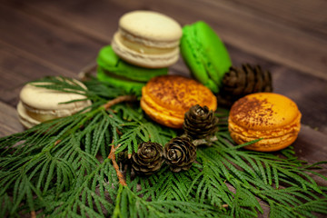 Colorful almond cookies and a Christmas tree with cones on a wooden table