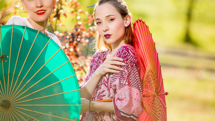 Beautiful  two women  in park wearing kimano and holding umbrella