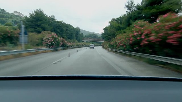 Driving on flower lined Sicilian highway. Driving from Messina to Palermo on Autostrada E90, Sicily, Italy.