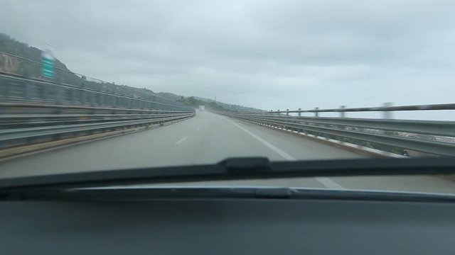 Crossing long curving bridge in the rain. Driving from Messina to Palermo on Autostrada E90, Sicily, Italy.