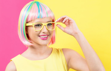 Young woman in a colorful wig with sunglasses on a split yellow and pink background