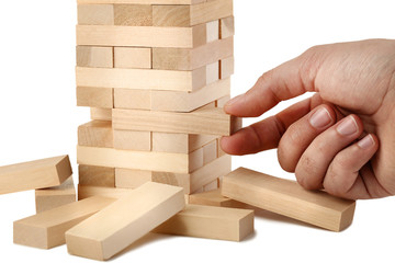 Male hand playing wooden blocks tower game on white background