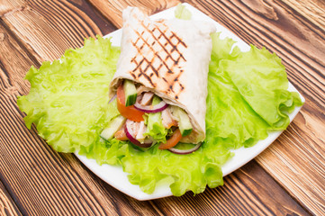 Shawarmas on lettuce isolated on a wooden background.