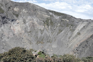 Irazu volcano in Costa Rica. Crater in clouds with protective barriers. Fragments of lava and pumice.