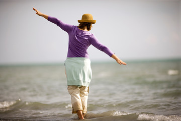 Mid-adult woman playing around in the shallow water of the sea.