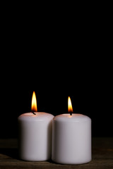 Fototapeta na wymiar White burning candles on black background