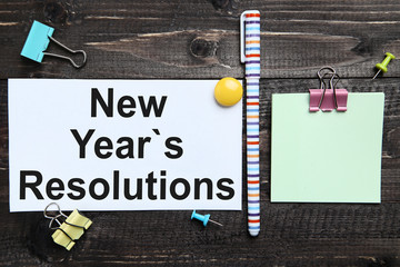 New year resolutions on sheet of paper with clips and pen