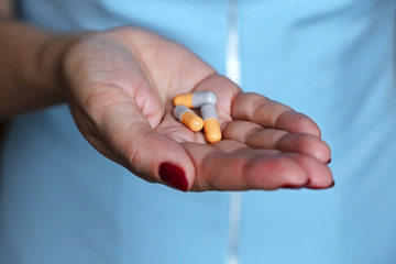 Pills in female hand close-up, woman doctor holding medication in capsules. Concept of pharmacist, drugs, antibiotics, treatment, medical prescription