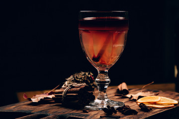 mulled red wine with spices and fruits on a wooden rustic table. Traditional hot drink at Christmas time