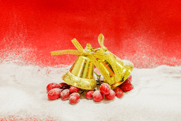 A pair of golden bells covered with snow on a red background