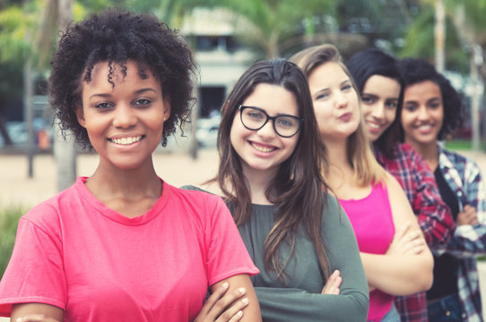 Laughing african american young adult woman with  international girls standing in line