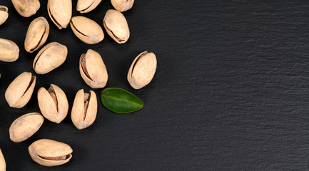 Pistachio nuts on a black slate board.