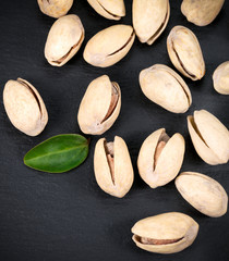 Pistachio nuts on a black slate board.