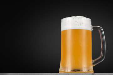 Glass of beer with foam on a dark background