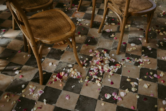 Wedding ceremony set up with wood chairs and flower petals on vintage 1900s checkered floor tile